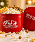 2 Gallon Signature Popcorn Tin - Red bucket of popcorn from Del's Popcorn Shop with 'Cooked Fresh Since 1934' text on a marble surface.