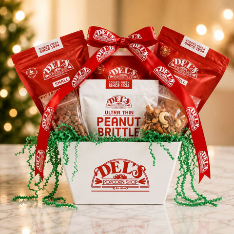 Del's Gourmet Gift Essentials Gift Box  with red bags and white box against a blurred festive background