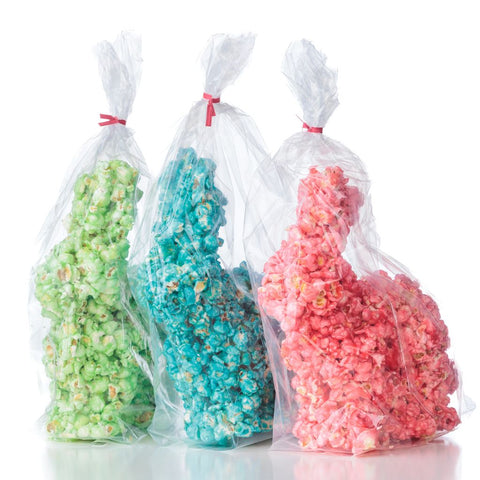 Three bags of colorful popcorn easter bunnies, one green, one blue, and one pink, packed with pink ribbons.