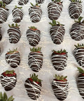 Chocolate-dipped strawberries with white drizzle on a white surface