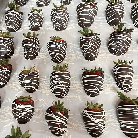 Chocolate-dipped strawberries with white drizzle on a white surface