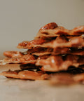 Stack of ultra thin, crispy peanut brittle with a blurred background